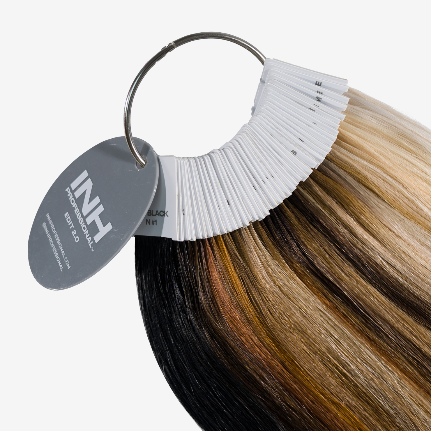 A hair color swatch ring fan showing multiple blended hair color options, including black, brown, blonde, and caramel tones, with a gray oval tag reading INH Colorswatch.